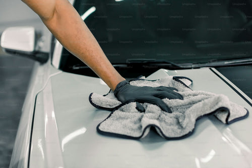 Hand cleaning car hood with foam cleaner